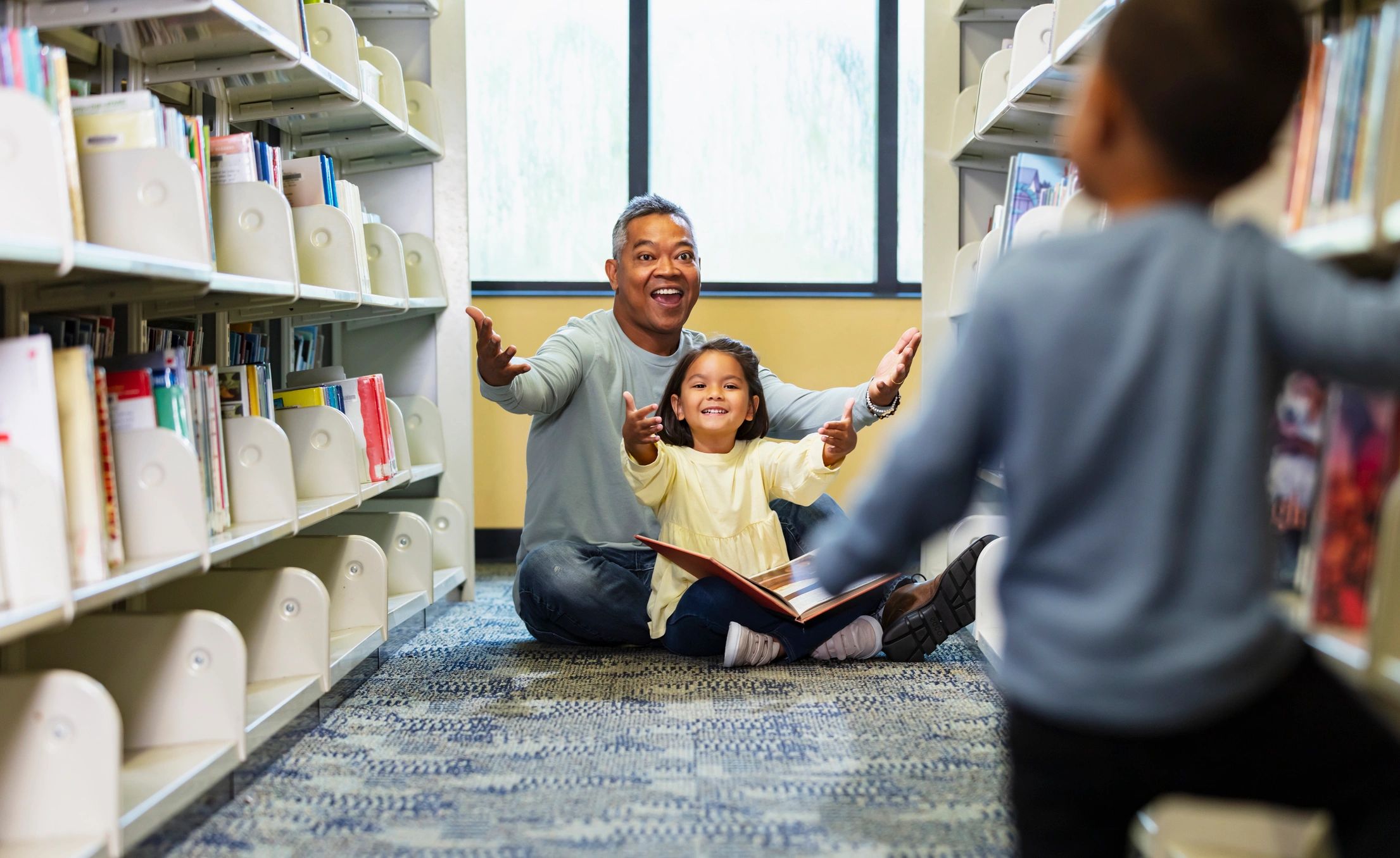 Caregiver and children reading together in a library